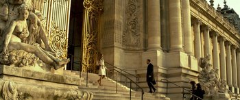Movie still from “3 Days to Kill” (2014), directed by McG – A man and a woman walking down the steps of a building; Wide shot, Low angle