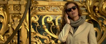 Movie still from “3 Days to Kill” (2014), directed by McG – A woman wearing sunglasses talking on a cell phone; Medium shot, Low angle