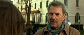 Movie still from “3 Days to Kill” (2014), directed by McG – An older man with a beard and a scarf; Close Up shot, Over the shoulder angle