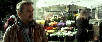 Movie still from “3 Days to Kill” (2014), directed by McG – A man standing in front of a bunch of flowers; Close Up shot, Low angle