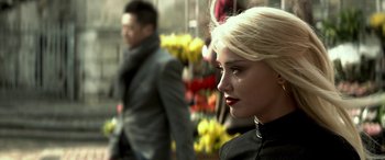 Movie still from “3 Days to Kill” (2014), directed by McG – A woman with blonde hair and red lipstick looking to her left; Close Up shot, Over the shoulder angle