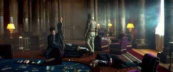 Movie still from “3 Days to Kill” (2014), directed by McG – A group of people in a room next to a table with cards; Wide shot, High angle