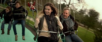 Movie still from “3 Days to Kill” (2014), directed by McG – A man and a woman on a swing ride at a park; Medium shot, Over the shoulder angle