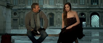Movie still from “3 Days to Kill” (2014), directed by McG – A man and a woman sitting on a bench in front of a building; Medium shot, Over the shoulder angle