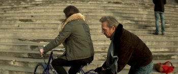 Movie still from “3 Days to Kill” (2014), directed by McG – A man and a woman riding a bike down the side of a ramp; Medium shot, Over the shoulder angle
