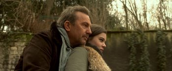 Movie still from “3 Days to Kill” (2014), directed by McG – A man and a woman sitting next to a body of water; Close Up shot, Low angle