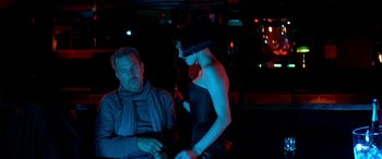 Movie still from “3 Days to Kill” (2014), directed by McG – A man and a woman are sitting in a dark room; Medium shot, Low angle