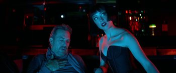 Movie still from “3 Days to Kill” (2014), directed by McG – A man and a woman are sitting in a dark room; Medium shot, Over the shoulder angle