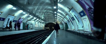 Movie still from “3 Days to Kill” (2014), directed by McG – A person walking on a train platform next to train tracks; Extreme Wide shot, High angle