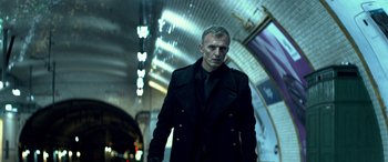 Movie still from “3 Days to Kill” (2014), directed by McG – A man wearing a black coat and a black tie; Medium shot, Low angle