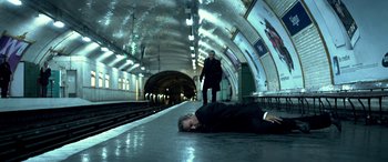 Movie still from “3 Days to Kill” (2014), directed by McG – A man laying on the floor of a train station next to another man; Wide shot, High angle