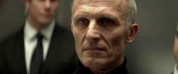 Movie still from “3 Days to Kill” (2014), directed by McG – An older man wearing a suit and tie; Close Up shot, Low angle