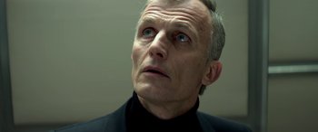Movie still from “3 Days to Kill” (2014), directed by McG – An older man in a black suit looking upward; Close Up shot, Low angle