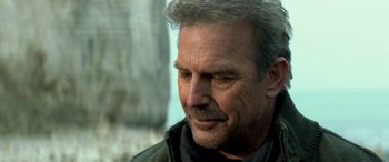 Movie still from “3 Days to Kill” (2014), directed by McG – An older man with grey hair looking to his left; Close Up shot, Over the shoulder angle