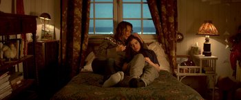Movie still from “3 Days to Kill” (2014), directed by McG – Two young women sitting on a bed in front of a window; Medium shot, High angle