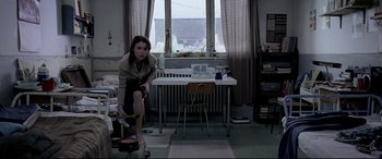 Movie still from “4 Months, 3 Weeks and 2 Days” (2007), directed by Cristian Mungiu – A woman sitting on a stool in front of a desk; Wide shot, High angle