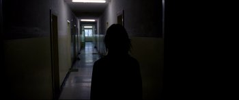 Movie still from “4 Months, 3 Weeks and 2 Days” (2007), directed by Cristian Mungiu – A woman standing in a dark hallway in the dark; Medium shot, Over the shoulder angle