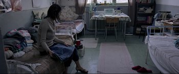 Movie still from “4 Months, 3 Weeks and 2 Days” (2007), directed by Cristian Mungiu – A woman sitting on a couch in a room; Wide shot, High angle