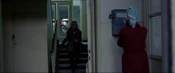 Movie still from “4 Months, 3 Weeks and 2 Days” (2007), directed by Cristian Mungiu – A woman walking down a set of stairs in a building; Wide shot, Over the shoulder angle