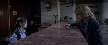 Movie still from “4 Months, 3 Weeks and 2 Days” (2007), directed by Cristian Mungiu – A person sitting at a counter with a tablet; Medium shot, High angle