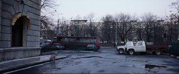 Movie still from “4 Months, 3 Weeks and 2 Days” (2007), directed by Cristian Mungiu – A bus parked in a parking lot next to a truck; Extreme Wide shot, High angle