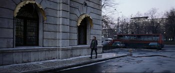 Movie still from “4 Months, 3 Weeks and 2 Days” (2007), directed by Cristian Mungiu – A woman walking down the street in front of a building; Wide shot, Low angle