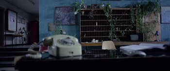 Movie still from “4 Months, 3 Weeks and 2 Days” (2007), directed by Cristian Mungiu – An old phone sitting on top of a desk; Wide shot, Low angle