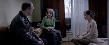 Movie still from “4 Months, 3 Weeks and 2 Days” (2007), directed by Cristian Mungiu – A woman sitting on a chair in front of two other people; Medium shot, Over the shoulder angle