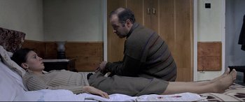 Movie still from “4 Months, 3 Weeks and 2 Days” (2007), directed by Cristian Mungiu – A man sitting on a bed with a woman; Medium shot, High angle