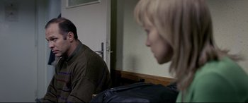 Movie still from “4 Months, 3 Weeks and 2 Days” (2007), directed by Cristian Mungiu – A man and a woman sitting in front of each other in a room; Medium shot, Over the shoulder angle