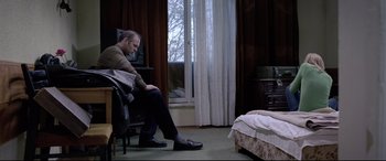 Movie still from “4 Months, 3 Weeks and 2 Days” (2007), directed by Cristian Mungiu – A man sitting in a chair in front of a window; Wide shot, High angle