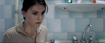 Movie still from “4 Months, 3 Weeks and 2 Days” (2007), directed by Cristian Mungiu – A woman sitting at a sink in a bathroom; Close Up shot, High angle