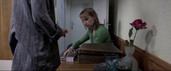 Movie still from “4 Months, 3 Weeks and 2 Days” (2007), directed by Cristian Mungiu – A woman sitting at a wooden table with a man; Medium shot, Over the shoulder angle