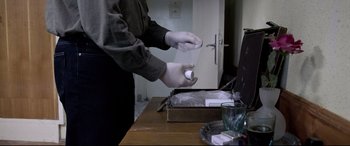 Movie still from “4 Months, 3 Weeks and 2 Days” (2007), directed by Cristian Mungiu – A person wearing gloves and holding a paper towel; Close Up shot, High angle