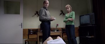 Movie still from “4 Months, 3 Weeks and 2 Days” (2007), directed by Cristian Mungiu – A man and a woman standing next to each other in a room; Medium shot, Over the shoulder angle