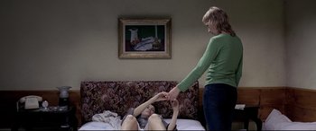 Movie still from “4 Months, 3 Weeks and 2 Days” (2007), directed by Cristian Mungiu – A woman standing next to a woman laying on a bed; Medium shot, Overhead angle