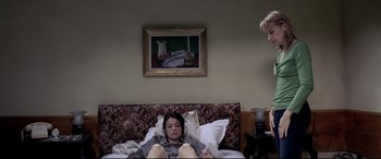 Movie still from “4 Months, 3 Weeks and 2 Days” (2007), directed by Cristian Mungiu – A woman laying on a bed with a painting on the wall behind her; Medium shot, Low angle