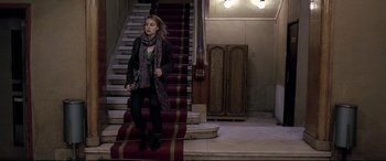 Movie still from “4 Months, 3 Weeks and 2 Days” (2007), directed by Cristian Mungiu – A woman standing on the bottom of a set of stairs; Wide shot, Low angle