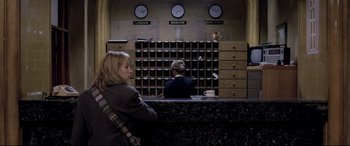Movie still from “4 Months, 3 Weeks and 2 Days” (2007), directed by Cristian Mungiu – Two women are sitting at a counter in front of a wall of clocks; Wide shot, Low angle