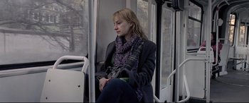 Movie still from “4 Months, 3 Weeks and 2 Days” (2007), directed by Cristian Mungiu – A woman sitting on a bus holding a drink; Medium shot, High angle