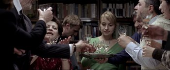 Movie still from “4 Months, 3 Weeks and 2 Days” (2007), directed by Cristian Mungiu – A group of people standing around a table with wine glasses; Medium shot, Over the shoulder angle