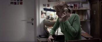 Movie still from “4 Months, 3 Weeks and 2 Days” (2007), directed by Cristian Mungiu – A woman holding a phone to her ear while sitting at a desk; Medium shot, High angle