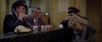 Movie still from “4 Months, 3 Weeks and 2 Days” (2007), directed by Cristian Mungiu – Two men sitting at a table with a cup of coffee; Medium shot, Over the shoulder angle