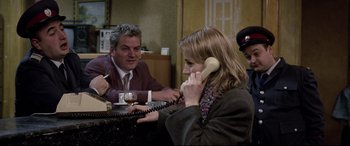 Movie still from “4 Months, 3 Weeks and 2 Days” (2007), directed by Cristian Mungiu – A woman talking on a phone while sitting next to a man; Medium shot, Over the shoulder angle