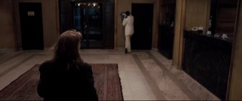 Movie still from “4 Months, 3 Weeks and 2 Days” (2007), directed by Cristian Mungiu – A man taking a picture of a woman in front of a door; Wide shot, Over the shoulder angle