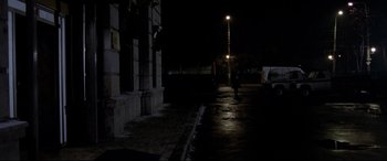 Movie still from “4 Months, 3 Weeks and 2 Days” (2007), directed by Cristian Mungiu – A person walking down a street at night; Extreme Wide shot, Over the shoulder angle