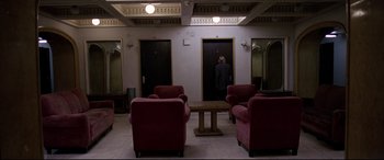 Movie still from “4 Months, 3 Weeks and 2 Days” (2007), directed by Cristian Mungiu – A man standing in a room next to a door way; Wide shot, High angle