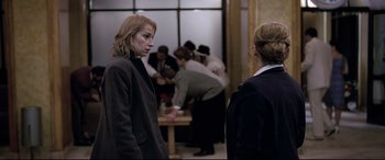 Movie still from “4 Months, 3 Weeks and 2 Days” (2007), directed by Cristian Mungiu – Two women are standing in front of a group of people; Medium shot, Over the shoulder angle
