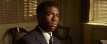 Movie still from “42” (2013), directed by Brian Helgeland – A man wearing a suit and tie in front of a window; Close Up shot, Low angle