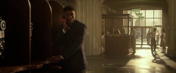 Movie still from “42” (2013), directed by Brian Helgeland – A man talking on a cell phone while standing next to a wall; Medium shot, Low angle